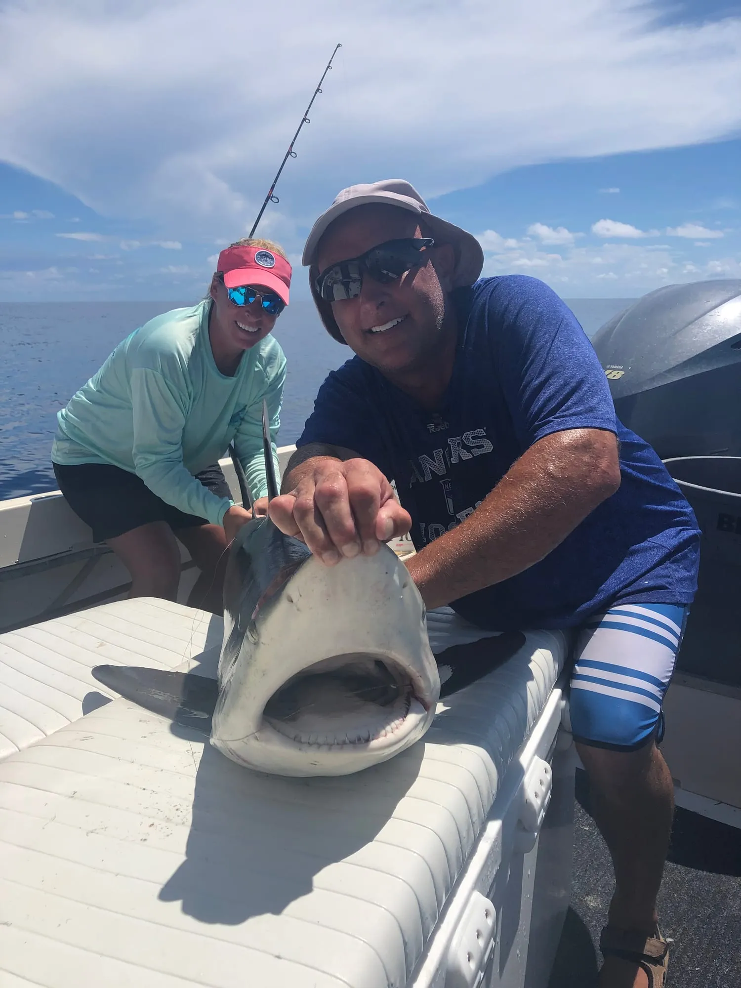 Two anglers holding a shark on deck