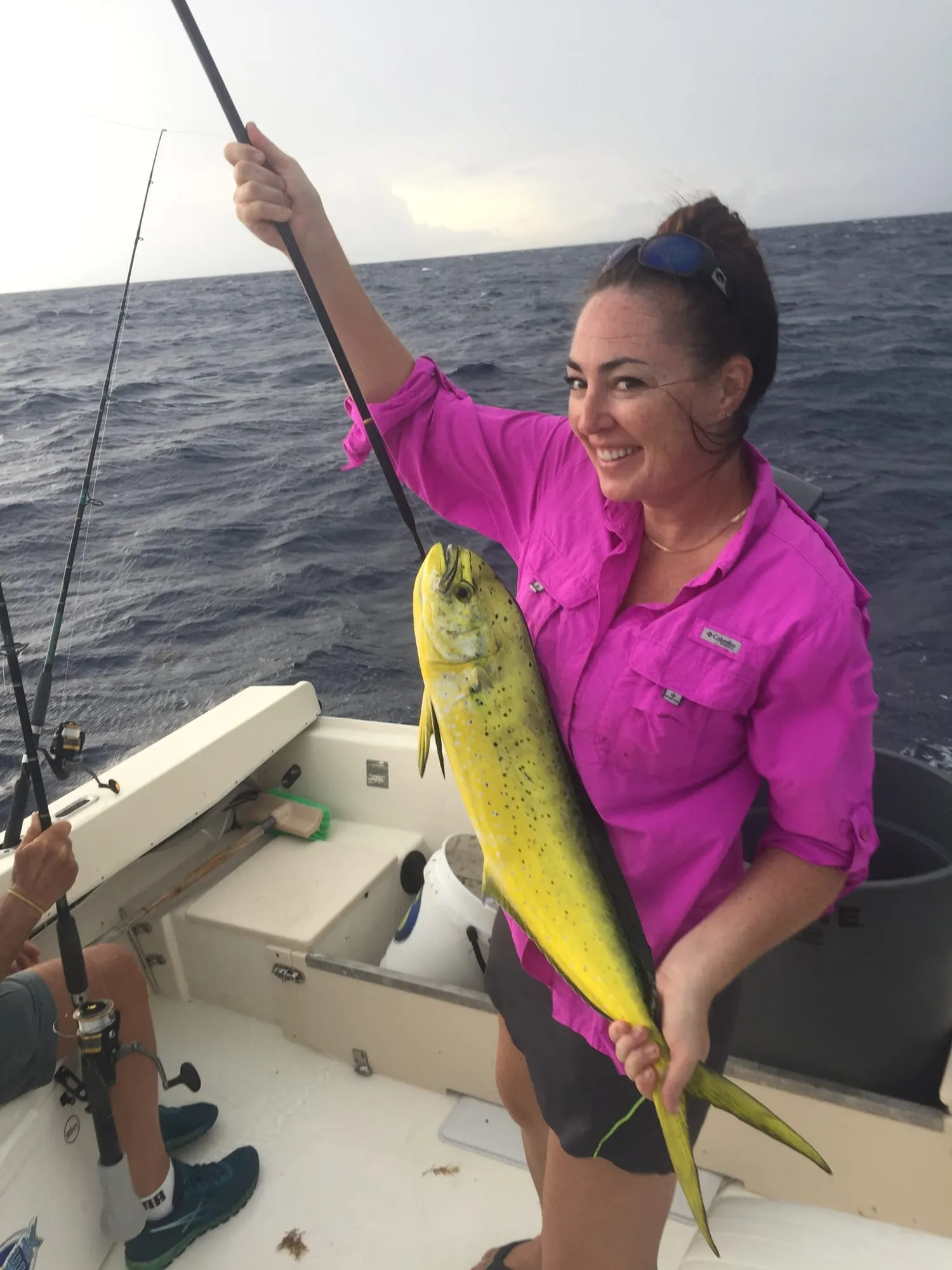 Angler in a pink shirt holding a mahi-mahi