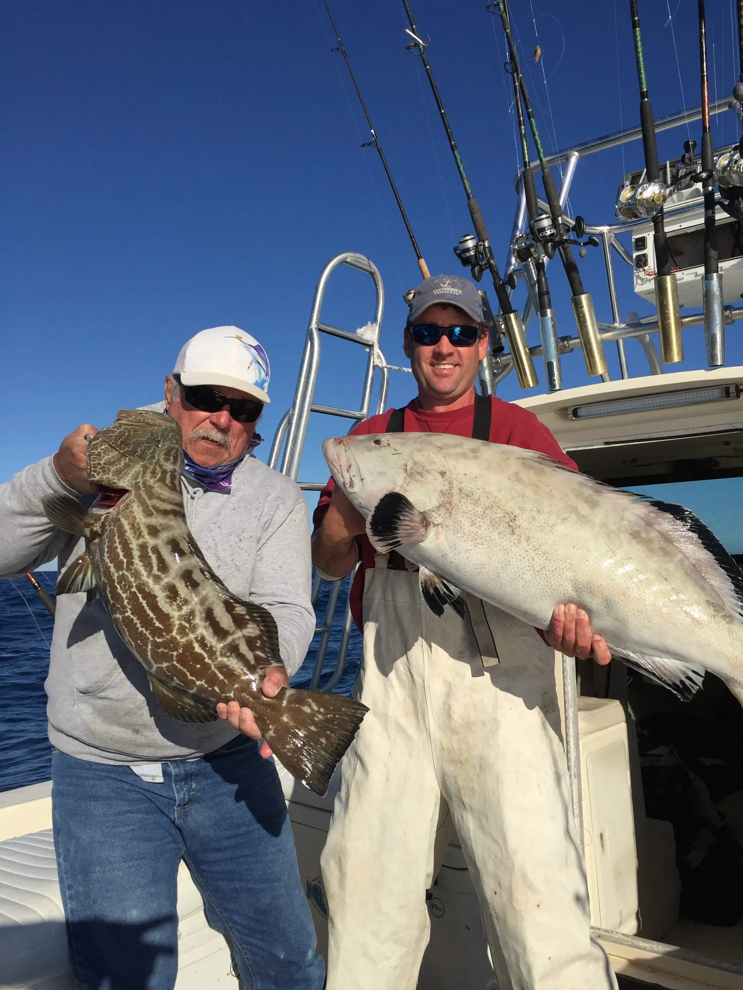 Anglers holding two large grouper aboard Satisfaction