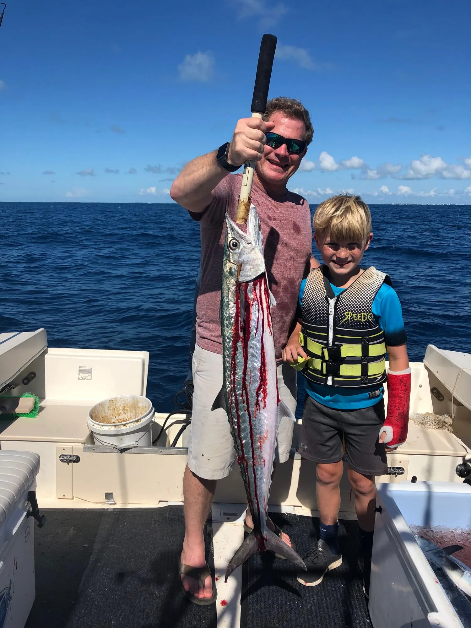 Young boy in a life jacket next to a big catch