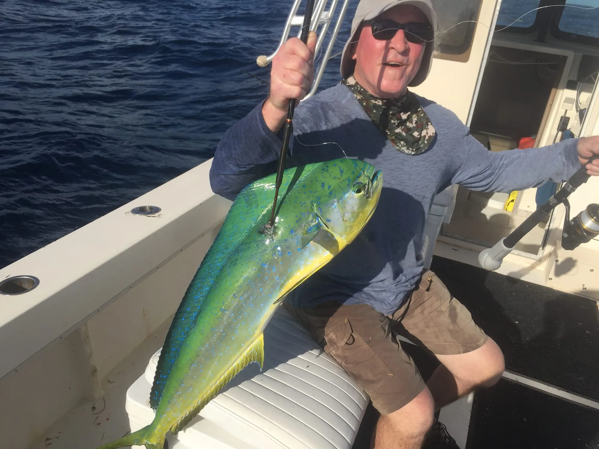 Angler holding up a big mahi-mahi aboard Satisfaction