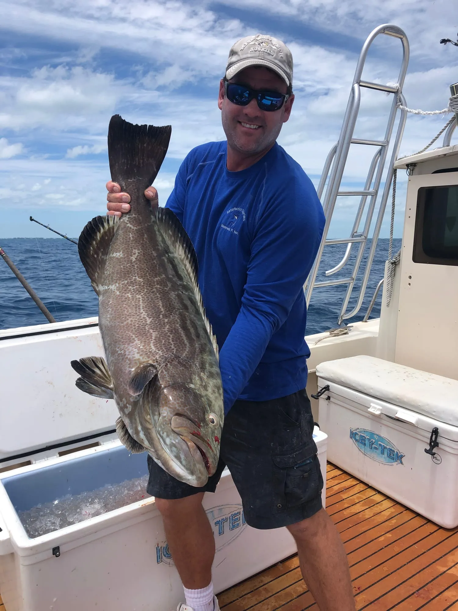 Angler holding a large grouper aboard Satisfaction