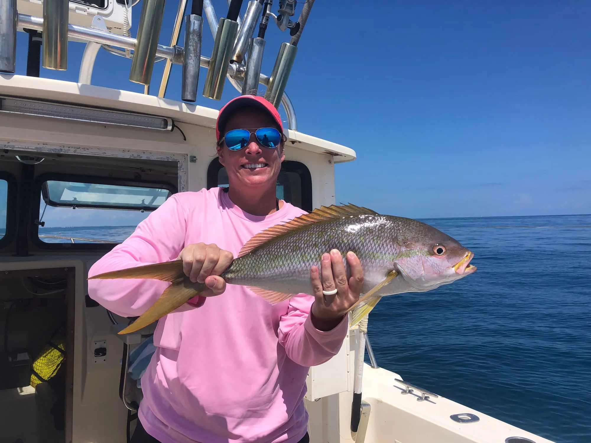 Angler in a pink shirt holding a yellowtail snapper